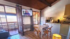Una piccola cucina con un tavolo da pranzo, sedie, una TV e una lampada.