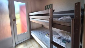 Una camera con letto a castello, una porta, una finestra e pavimento piastrellato.