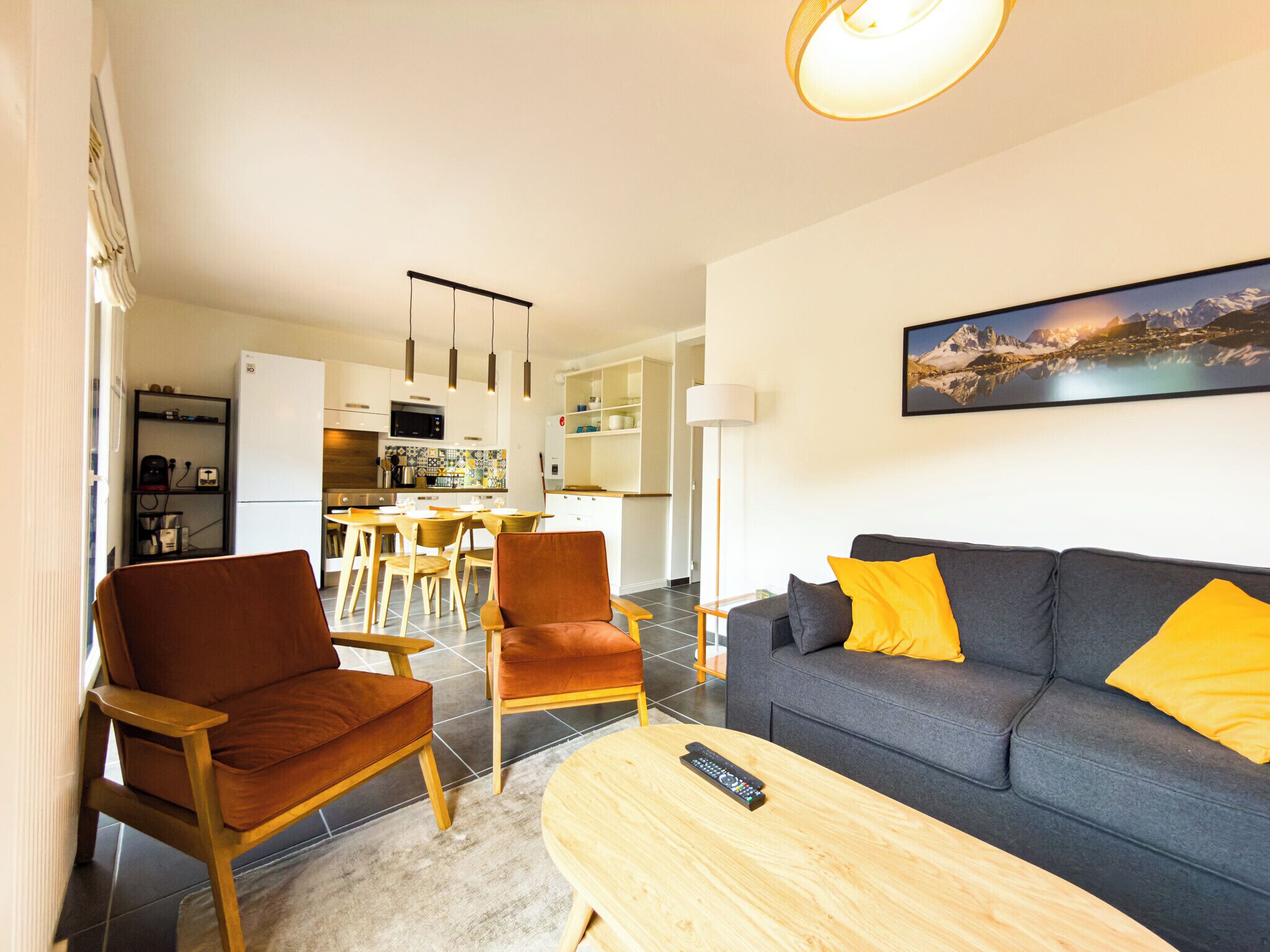 A modern living room with a sofa, chairs, a coffee table, and a kitchen in the background.