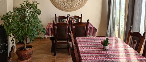 A dining area with a round table, chairs, a potted plant, and a decorative wall piece.