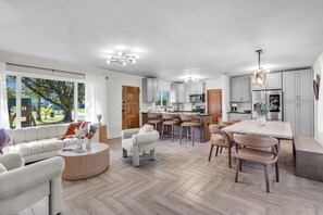 Una cocina moderna con armarios grises, una isla central y un comedor con mesa y sillas de madera.