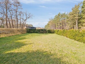 A grassy outdoor area with a building in the background, surrounded by trees and bushes. - 5 Star Holiday Home in Romo (Rømø)