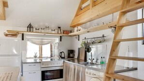 Cozinha com forno embutido, máquina de lavar e mezanino de madeira.