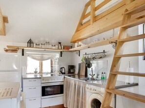 Eine Küche mit Einbauofen, Waschmaschine und einem Holzlofte.
