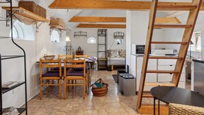 Um espaço compacto com área de refeições, cama, cozinha e um mezanino acessado por escada.
