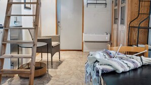 Quarto com escada de madeira, móveis de vime, cesta trançada e mesa com materiais de tricô.
