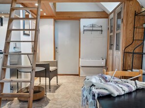 Ein Zimmer mit einer Holzleiter, Korbmöbeln, einem gewebten Korb und einem Tisch mit Strickzeug.