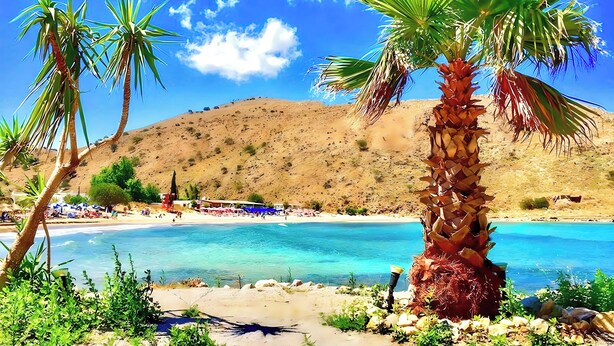 A beach with clear blue water, palm trees, and a sandy shore. - Sunlight Villa Heated Pool (Georgioupoli)