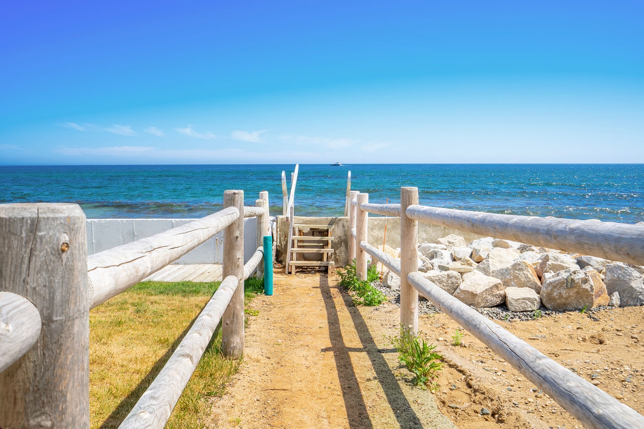Un sentiero in legno conduce a una spiaggia con vista libera sull'oceano.