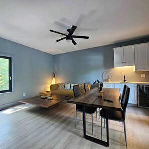 Eine moderne Küche mit weißen Schränken, ein Essbereich mit einem Holztisch und Stühlen sowie ein Deckenventilator.