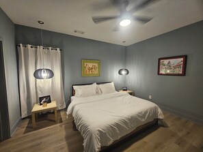 Ein Schlafzimmer mit Bett, Nachttischen, Deckenventilator und Wandbildern.