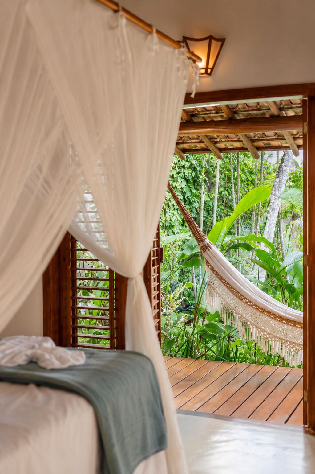 Ein Zimmer mit Bett, Hängematte und Blick auf üppiges Grün.