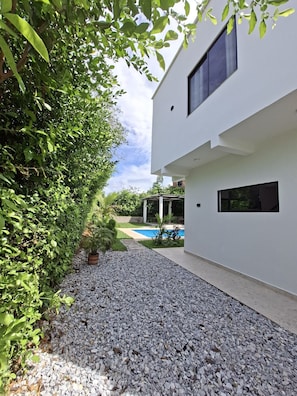 A modern building with a swimming pool, surrounded by gravel and greenery.