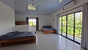 Una camera da letto con un letto, un letto aggiuntivo, una ventola a soffitto, una finestra e un condizionatore.