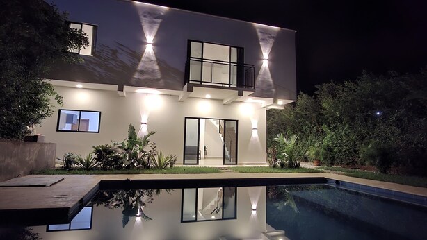 Una casa moderna con piscina, un balcone e un esterno luminoso.
