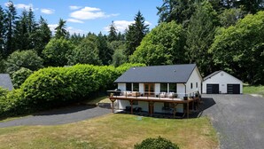 A two-story house with a deck, a garage, and a well-maintained lawn. - Hidden Harbor Getaway-Sunrise Views-Private Beach Access (Gig Harbor)