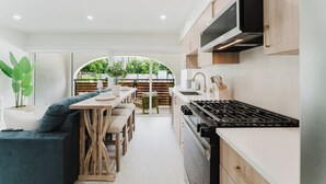 A modern kitchen with a dining area, white cabinetry, and a view to the outdoors. - Villa Solana: Boca Pool Hideaway (Boca Raton)