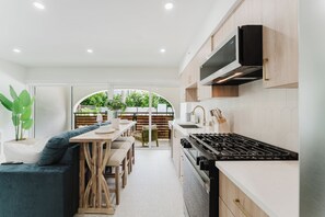 A modern kitchen with a dining area, white cabinetry, and a view to the outdoors. - Villa Solana: Boca Pool Hideaway (Boca Raton)