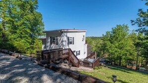 A two-story house with a deck and stairs leading to a front porch.
