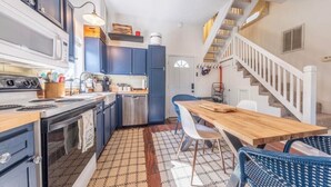 A compact kitchen with a dining area, a staircase, and a patterned floor.