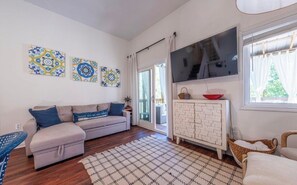 Un saló amb un sofà, una televisió, una catifa amb dibuixos i decoració mural.