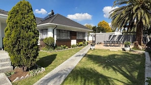 A residential house with a paved driveway, a lawn, and a patio area with outdoor furniture. - Bella Vista Airbnb (Edenvale)