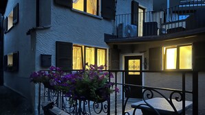 A building with a balcony, a door with a decorative glass panel, and a window with curtains.