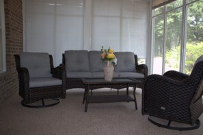 Ein Zimmer mit grauem Sofa, einem kleinen Tisch und einer Vase mit Blumen.