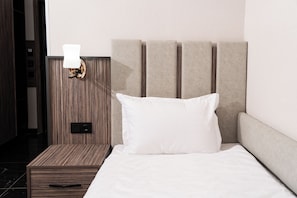 A neatly made bed with a white pillow and a headboard with vertical slats. - Gulshan Hotel (Urgench)
