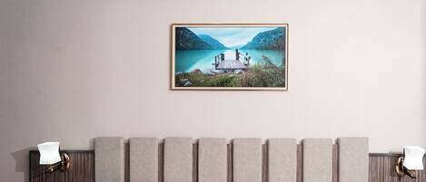 A double bed with a wooden headboard, two bedside tables with lamps, and a framed landscape painting above.