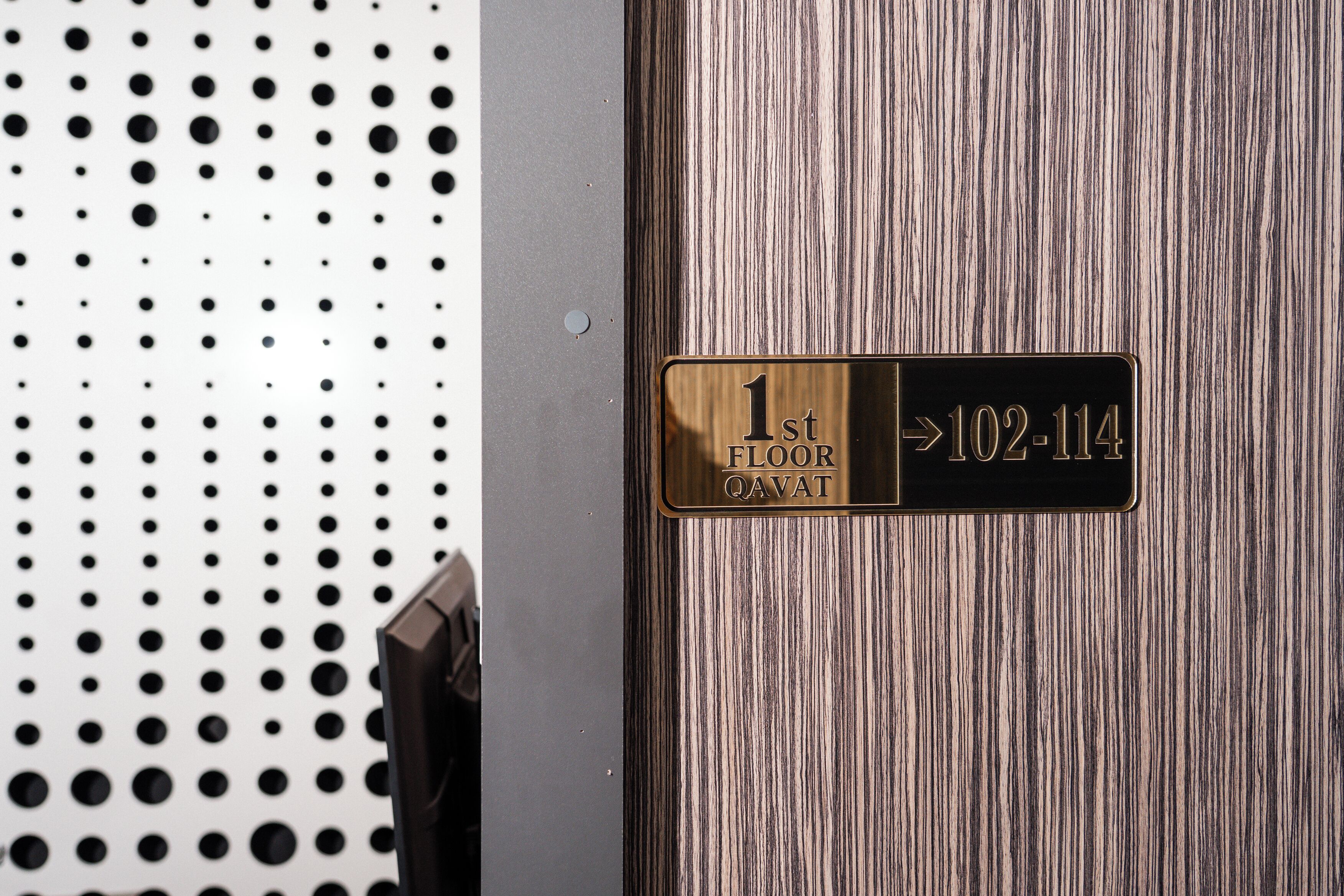 A hotel room door with a sign indicating '1st FLOOR QAVAT' and a room number '102-114'.