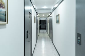 A long, narrow hallway with doors on both sides, a clean floor, and a ceiling light. - Gulshan Hotel (Urgench)