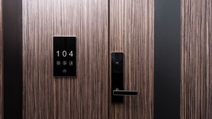 A wooden elevator door with a digital display showing the number 104 and a control panel. - Gulshan Hotel (Urgench)
