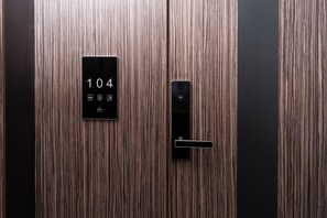 Eine Holztür des Aufzugs mit einer digitalen Anzeige für die Zahl 104 und einem Bedienfeld.