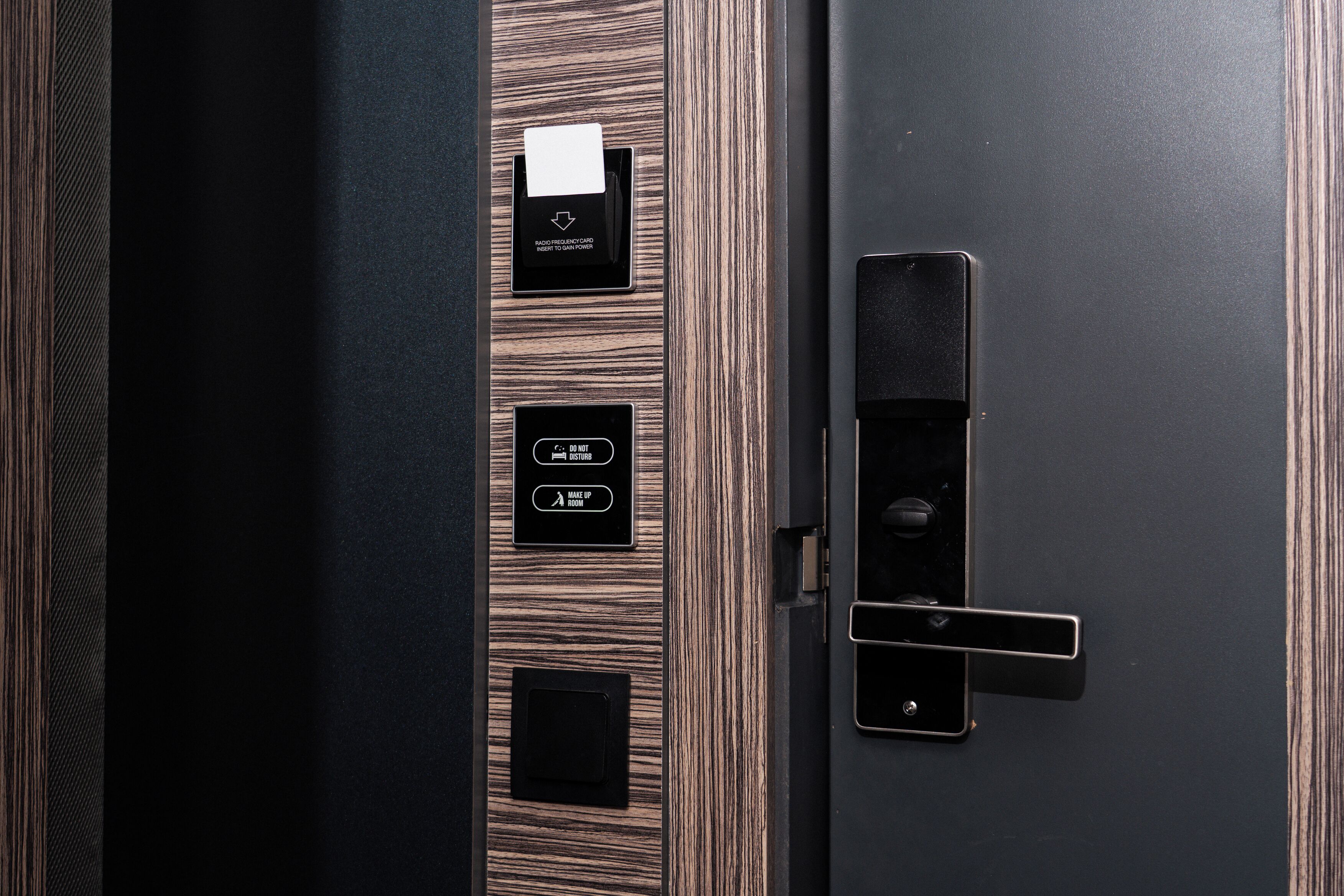 A modern door with a keycard reader, a card slot, and a push button for room access.