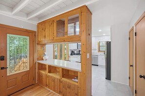A wooden cabinet with glass doors, a white countertop, and a kitchen area with cabinets and appliances. - Sharp Top Mountain Retreat (Jasper)