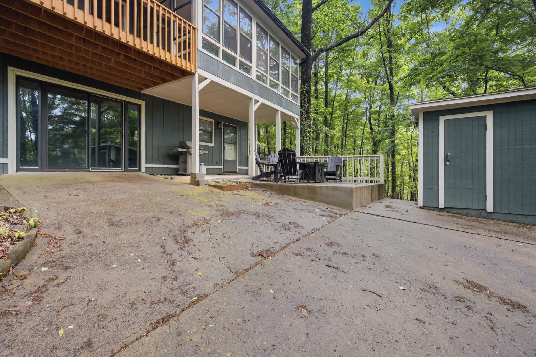 Ein zweistöckiges Haus mit überdachter Terrasse, einer Holzterrasse und einer Garage.