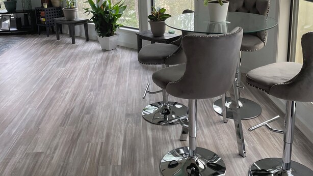 A modern dining area with a round glass table, grey upholstered chairs, and potted plants. - Cozy 2-bedroom house in amazing Myrtle Beach with AC (Myrtle Beach)