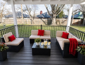 A covered outdoor seating area with three sofas and a coffee table, surrounded by a wooden deck and a black railing. - Game Day Haven — 8 min Walk to AT&T Stadium —Sleeps 10 (Arlington)