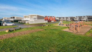 Et boligområde med moderne huse, en legeplads og parkeringsplads.
