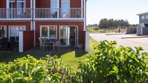 En toetagers bygning med balkon, udendørs siddepladser og en græsplæne.