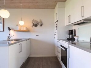 Eine moderne Küche mit weißen Schränken, einem eingebauten Backofen und einer Kaffeemaschine.