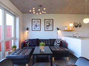 Ein stilvoller Wohnbereich mit einer Sofagarnitur, einem Couchtisch und einer Küchenzeile inklusive Spüle und Geschirr.