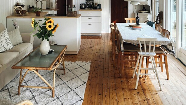 A spacious room with a high ceiling, a dining area with wooden furniture, and a cozy seating area with a sofa and a table. - Personal style in a home between Vig and Høve (Vig)
