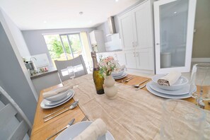 A dining table set with plates, cutlery, a vase with flowers, and a bottle.