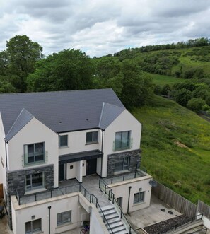 A modern two-story house with a sloped roof, large windows, and a stone facade.