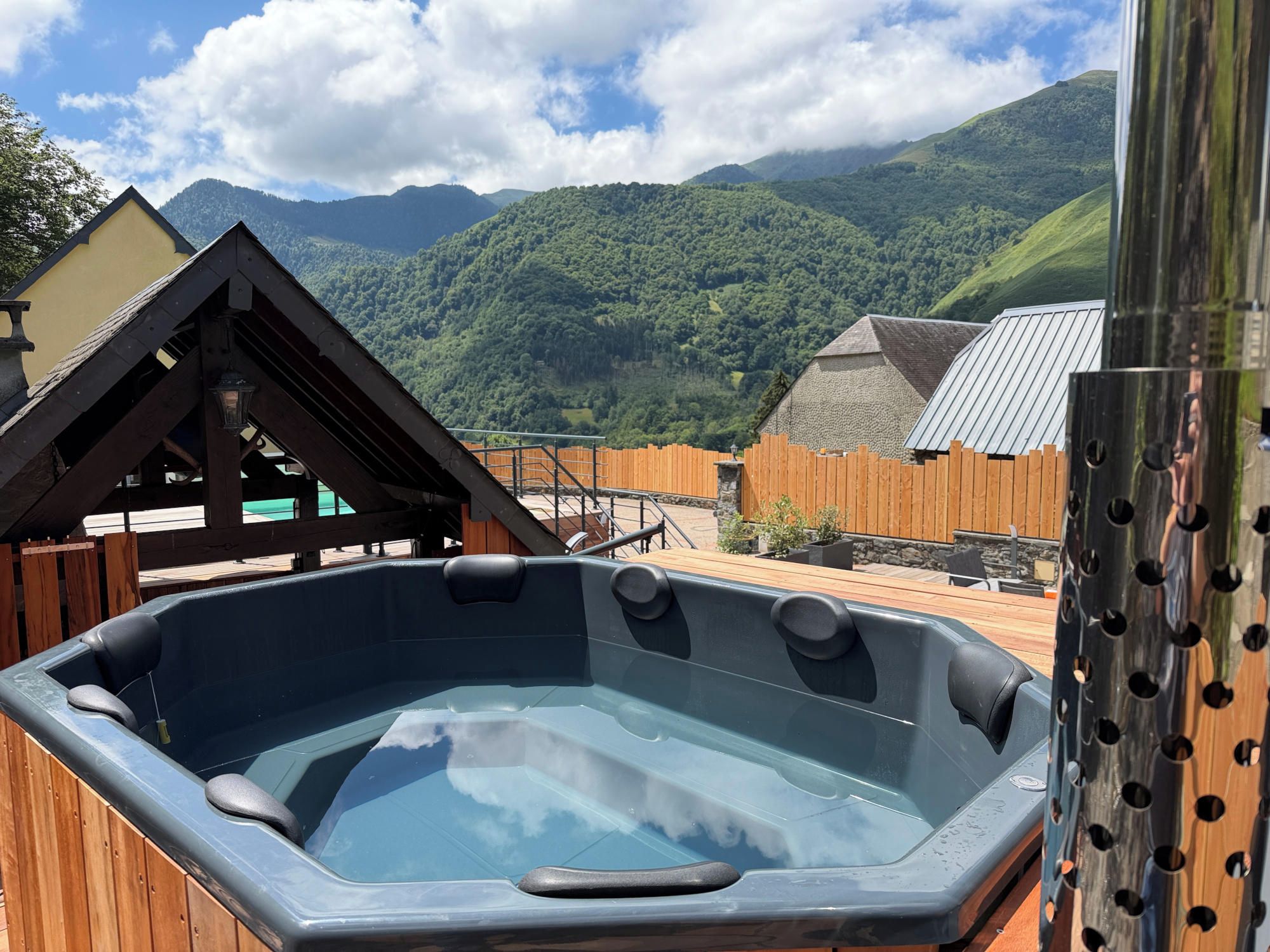 Un bain à remous avec une terrasse en bois et une vue sur les montagnes en arrière-plan.