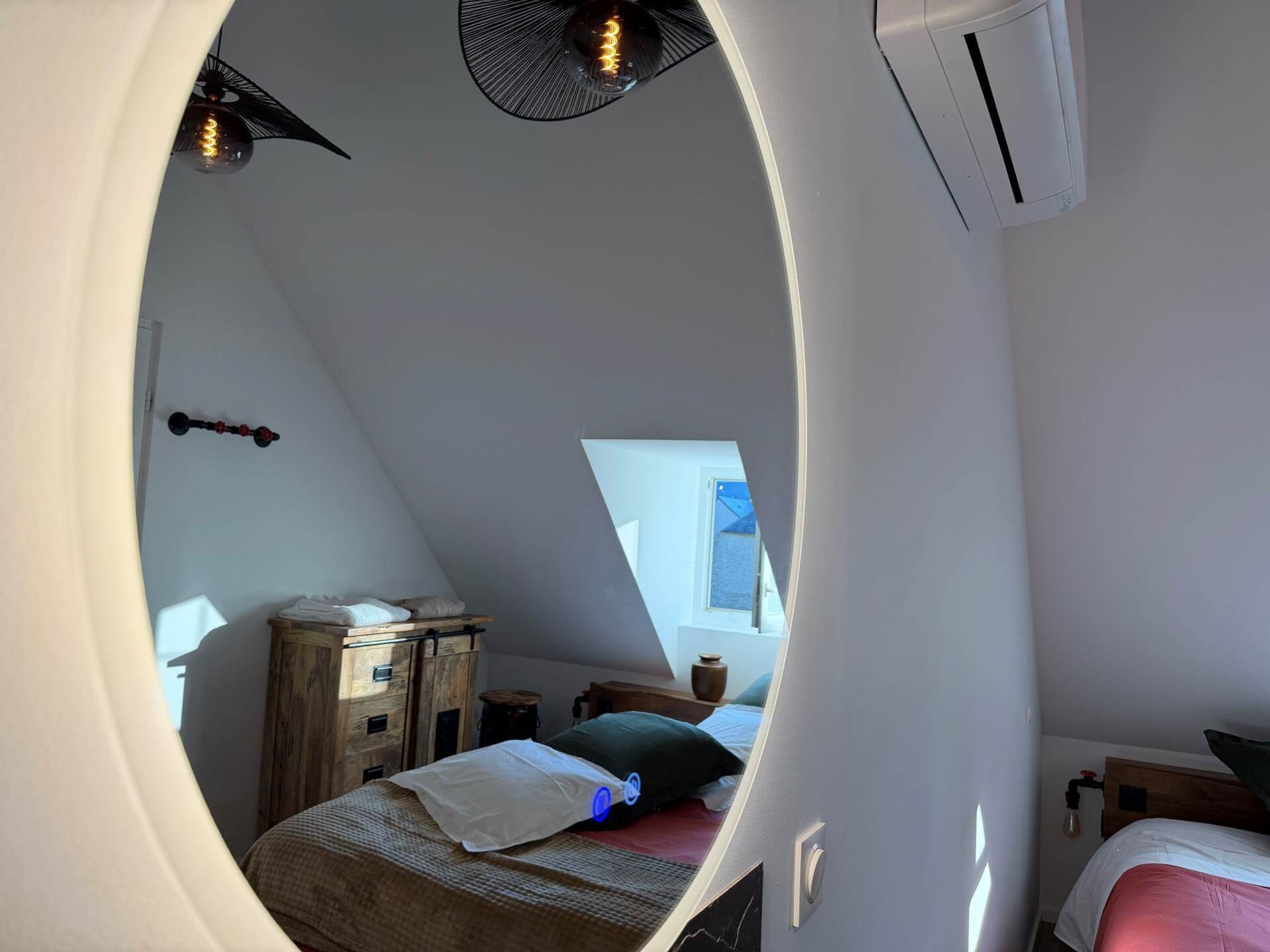 Une chambre à coucher comprenant un lit, une commode en bois, une fenêtre et un appareil de climatisation.