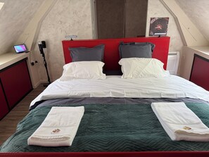 A neatly made bed with white linens, two pillows, and a green quilt.