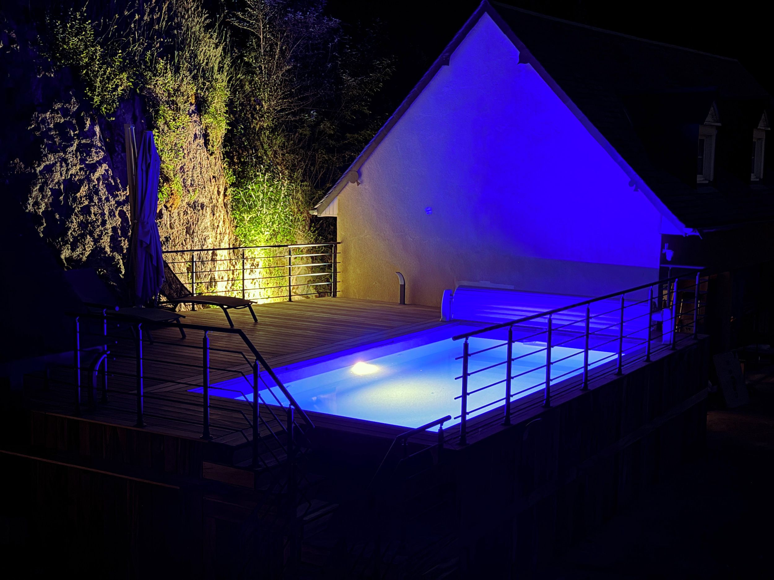 Une piscine dotée d’une terrasse en bois et d’une rambarde en métal.